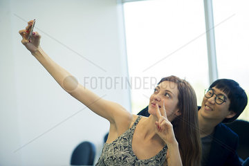 Woman making peace sign while taking selfie with friend