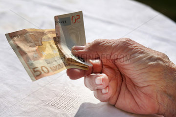 Berlin  Deutschland  die Hand einer Rentnerin mit einem Euroschein