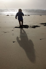 Pajara  ein kleines Kind laeuft am Strand entlang