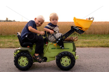 Kinder fahren mit einem Kinderspielzeugtraktor