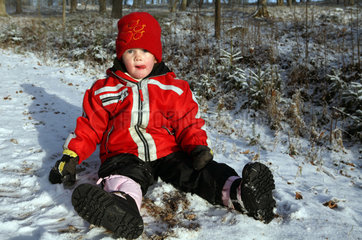 Belloe  Schweden  Kind in Winterkleidung sitzt auf schneebedecktem Boden