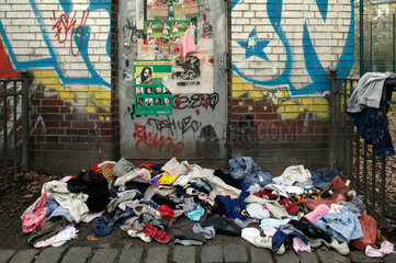 Berlin  Deutschland  Kleidungsstuecke liegen auf der Strasse vor einer beschmierten Tuer