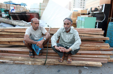 Dubai  Vereinigte Arabische Emirate  Maenner sitzen auf einem Stapel Holzplanken
