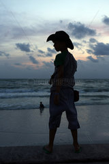 Pass A Grille  Vereinigte Staaten von Amerika  Silhouette  Junge mit Cowboyhut steht bei Daemmerung am Strand
