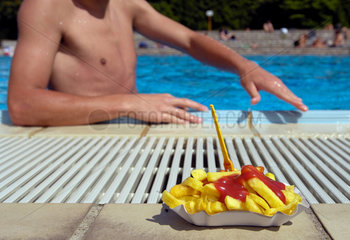 Berlin  Deutschland  Badener in einem Freibad greift nach einer Portion Pommes