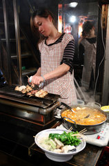 Tokio  Japan  Frau bereitet Fleischspiesse zu