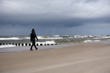 Kolberg  Polen  Frau laeuft bei Regenwetter allein am Strand entlang