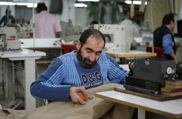 Istanbul  Tuerkei  Mitarbeiter naeht Knoepfe an Maentel in einer Textilfabrik an