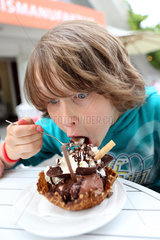 Werl  Deutschland  Junge isst eine Waffel mit Schokoladeneis und Sahne