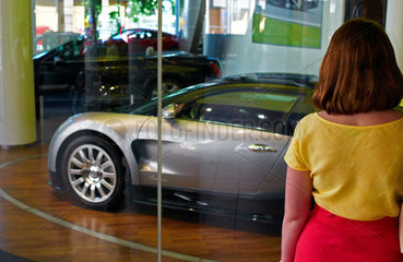 Berlin  Deutschland  Frau betrachtet einen Bugatti in einem Schaufenster