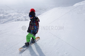 Krippenbrunn  Oesterreich  ein Junge steht auf seinem Snowboard an einem steilen Hang