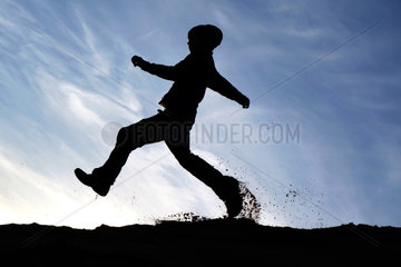 Schependorf  Deutschland  Silhouette  ein Junge rennt ueber einen Sandhuegel