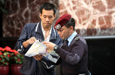 Macau  China  Polizist zeigt einem Mann den Weg auf einem Stadtplan