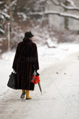 Berlin  Deutschland  Seniorin laeuft einen schneebedeckten Gehweg entlang