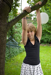 Berlin  Deutschland  ein Maedchen haelt sich im Garten an einem Baum fest