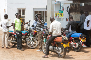 Kamdini  Uganda - Strassenszene. Motorradfahrer warten an einer Zapfsaeule einer Tankstelle betankt zu werden.
