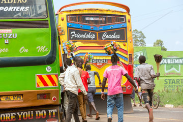Kamdini  Uganda - Fliegende Haendler an einem Busstop. Einheimische laufen einem Ueberlandbus mit Waren hinterher.
