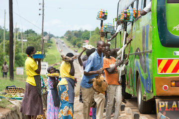Kamdini  Uganda - An einem Busstop bieten Fliegende Haendler Reisenden eines Ueberlandbusses Waren zum Verkauf an.