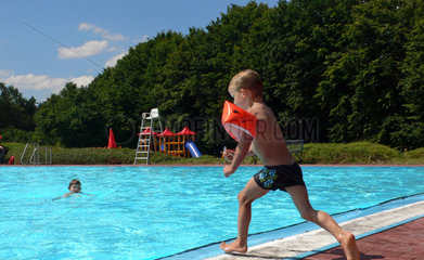 Werl  Deutschland  Junge mit Schwimmfluegeln springt ins Wasser
