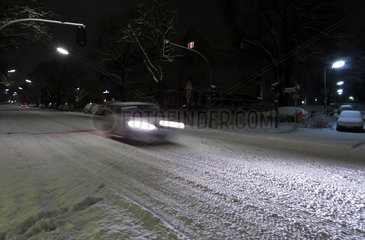Berlin  Deutschland  Auto faehrt bei Nacht auf einer verschneiten Strasse