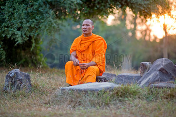 Angkor  Kambodscha  ein Moench sitzt auf einem Stein