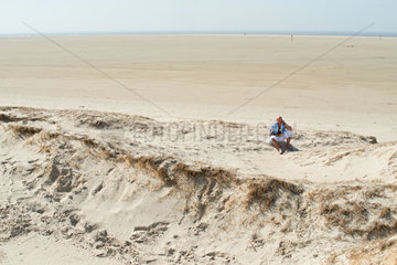 Sankt Peter-Ording  Deutschland  ein Mann sitzt im Sand und telefoniert