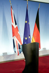 Berlin  Deutschland - Die Fahnen von Grossbritannien  der Europaeischen Union und Deutschlands haengen an Standarten hinter zwei Stehpulten vor einer Logowand in einem Presseraum des Aussenministeriums.