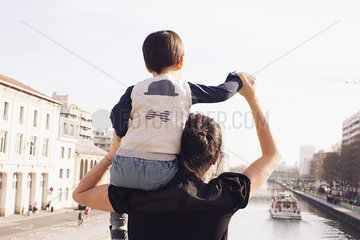 Mother carrying little boy on shoulder  looking at view together