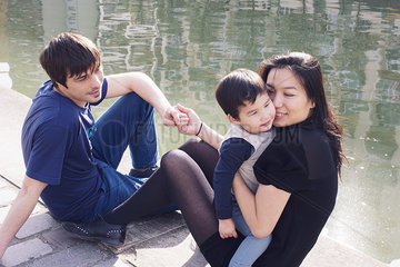 Parents and little boy hanging out on riverbank