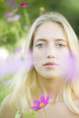Young woman among cosmos flowers  portrait