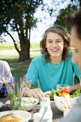 Young man enjoying meal with friends outdoors