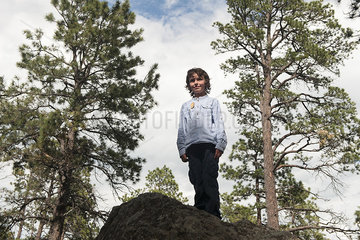 Boy standing on large rock in woods