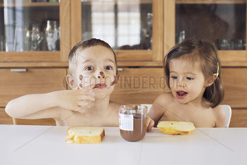 Siblings enjoying chocolate spread and toast for snacks