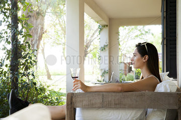 Woman relaxing on veranda with glass of wine