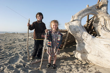 Children standing beside driftwood on beach