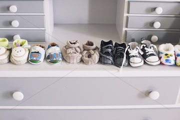 Row of baby shoes on top of dresser