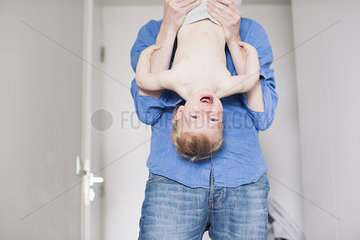 Father holding baby upside down
