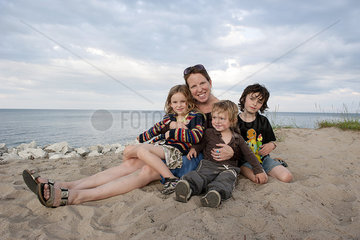 Mother and children sitting together on beach  portrait