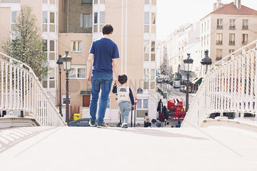 Father and little boy walking on bridge