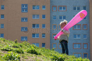 Berlin  Deutschland  Kleines Maedchen mit pinkfarbener Keule vor einem Plattenbau