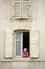 Nancy  Frankreich  eine aeltere Frau schaut aus dem Fenster eines alten Mietshauses