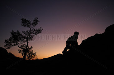 Vaestervik  Schweden  Silhouette  Kind klettert im Abendlicht einen Huegel hinauf