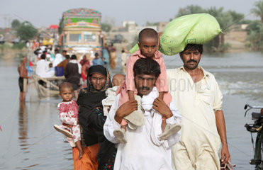 Muzaffargarh  Pakistan  Menschen durchwaten ueberflutete Strassen