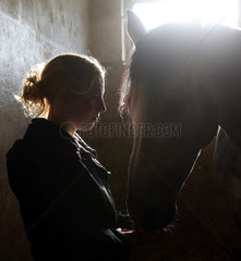 Neuenhagen  Deutschland  Silhouette  Frau und Pferd in einer Pferdebox