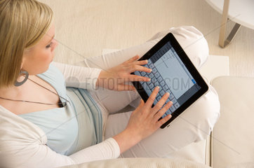 Hamburg  Deutschland  eine junge Frau sitzt mit ihrem iPad auf der Couch