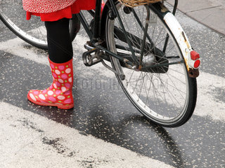 Kopenhagen  Daenemark  Fahrradfahrerin mit bunten Gummistiefeln