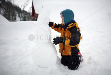 Krippenbrunn  Oesterreich  Kind baut einen Schneemann