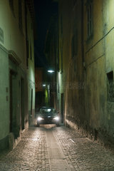 Tirano  Italien  ein Auto faehrt bei Nacht durch eine Gasse