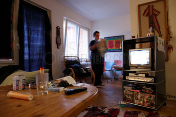 Berlin  Deutschland  Eine junge Frau raeumt in ihrem Wohnzimmer auf