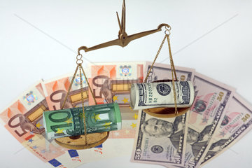 Eine Waage mit Dollar- und Euroscheinen im Ungleichgewicht